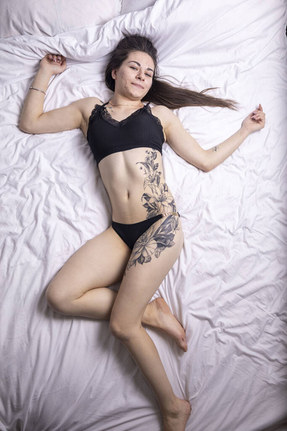 Kijev, Ukrajna - február 05. 2024 Egy lány tetoválással az ágyon. - Fotó, kép
