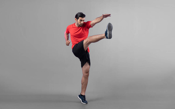 Full body length gaiety shot athletic and sporty young man with fitness in cardio exercise, kicking position posture on isolated background. Healthy active and body care lifestyle. - Photo, Image