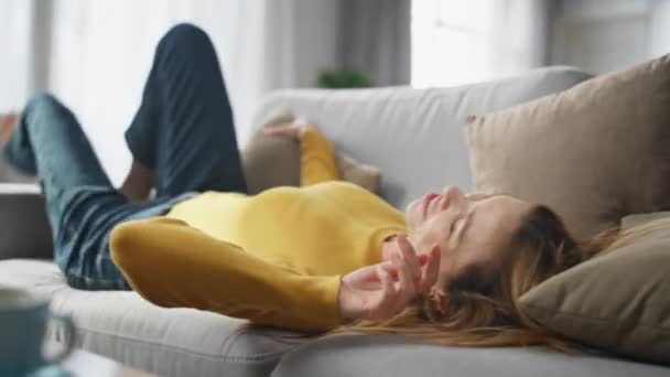 Joyful model falling couch hugging pillow at home closeup. Carefree happy woman taking mobile phone checking message with smile. Positive lazy lady messaging smartphone enjoying weekend at apartment - Footage, Video