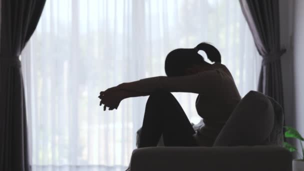 Silhouet van de vrouw die lijdt aan depressie ligt op de bank, heeft stress, angst, ziekte en hoofdpijn, levensproblemen, huiselijk geweld, geestelijke gezondheid, gedachten aan zelfmoord.  - Video