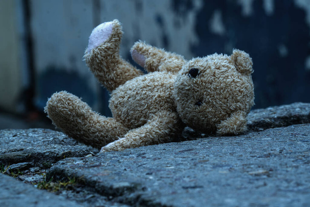 Imagen conceptual: La infancia perdida y el concepto de vida rota. El oso de peluche está acostado sobre el asfalto sucio.   - Foto, Imagen