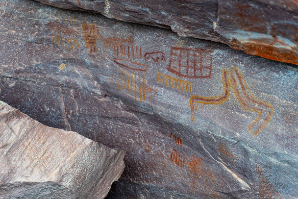 Coloridos petroglifos antiguos con imágenes simbólicas grabadas en piedra capturadas en una fotografía detallada. - Foto, Imagen