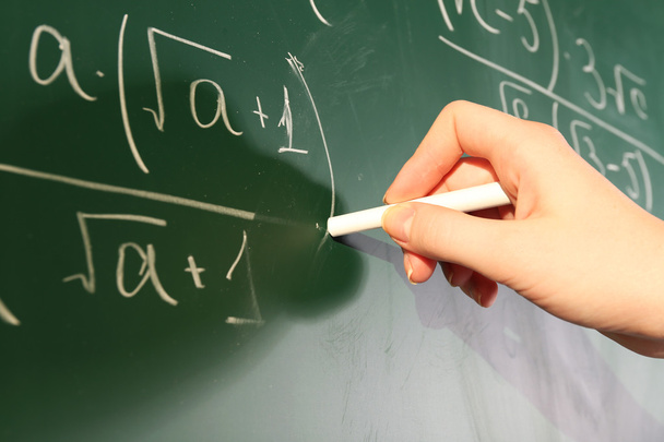 Teacher hand writing formulas on blackboard background - 写真・画像