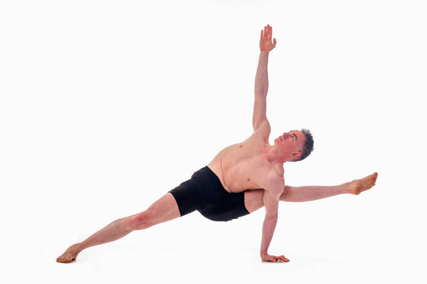 Vasisthasana, Ashtanga yoga Side view of man wearing sportswear doing Yoga oefening tegen witte achtergrond.  - Foto, afbeelding