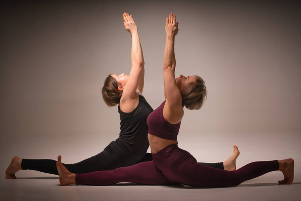 Hanumanasana (Triangle Pose), Ashtanga yoga Vista lateral de las mujeres que usan ropa deportiva haciendo ejercicio de yoga  - Foto, Imagen