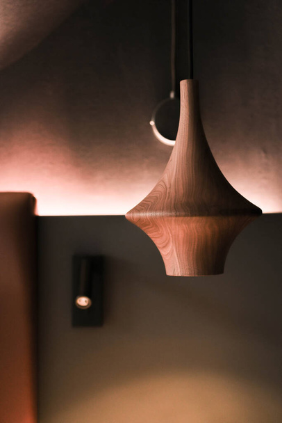 A wooden light fixture suspended from the ceiling of a hotel room, providing illumination and style. - Photo, Image