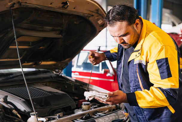 Garage meccanico automatico di lavoro controllare il livello dell'olio motore bastone nel centro di assistenza auto, indiano professionale maschile di lavoro - Foto, immagini