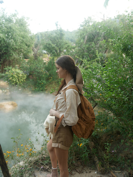 Una donna in piedi accanto a un fiume con uno zaino sulla schiena - Foto, immagini