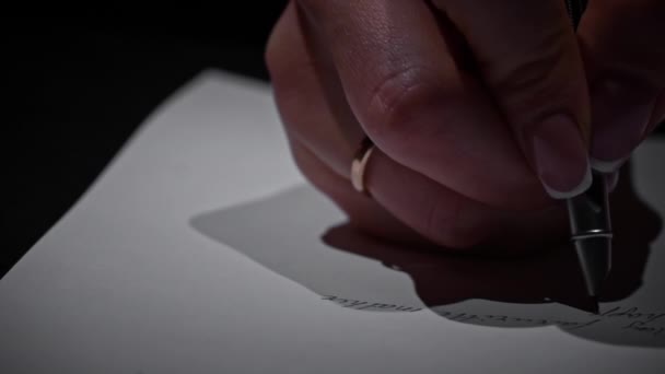 Ręka Mans pisze antycznym długopisem na białym papierze z bliska. Pisze list kaligraficzny używając zabytkowego pióra i tuszu na kartce białego papieru. Napisz wielką literą przy świecach.. - Materiał filmowy, wideo