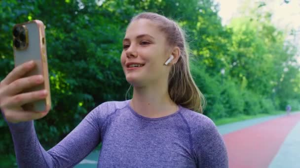 Vrouw in sportkleding op schema pratend via mobiele telefoon en wegrennend  - Video