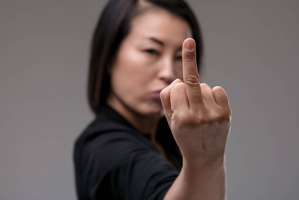 Com um olhar de desdém, uma mulher de descendência japonesa rejeita firmemente golpes e truques, seu gesto expressando sua postura dura. - Foto, Imagem
