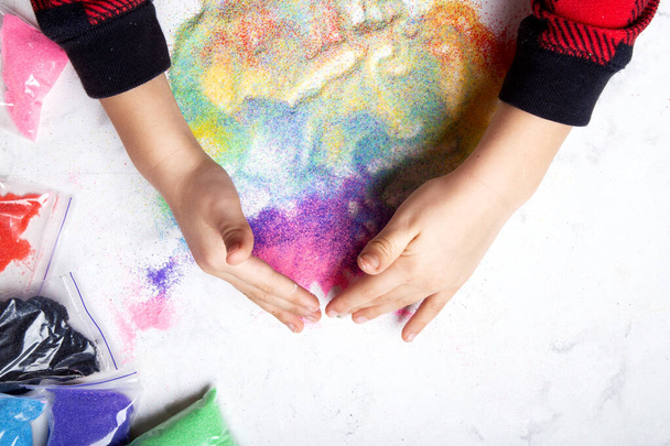 Творческая игра с разноцветным песком. Моторные навыки, концепция детского творчества. - Фото, изображение