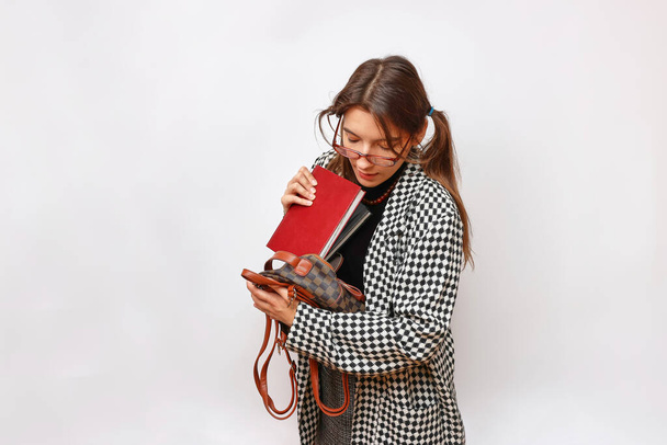 Egy szemüveges diák és egy hátizsák könyveket tart a kezében.. - Fotó, kép