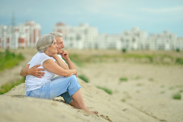 Elderly couple sitting on sand - Foto, Bild