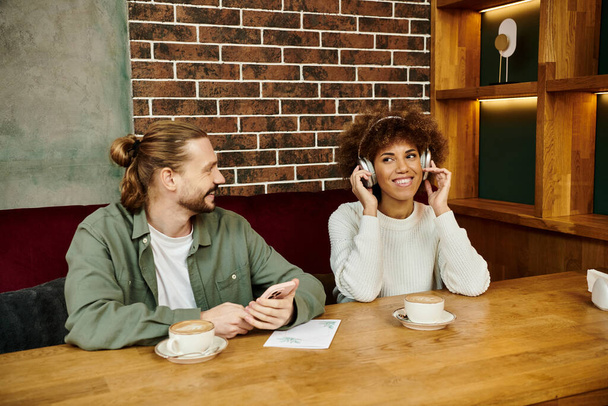 Afro-Amerikalı bir kadın ve erkek kafeterya masasında otururken cep telefonu konuşmalarına dalmış.. - Fotoğraf, Görsel