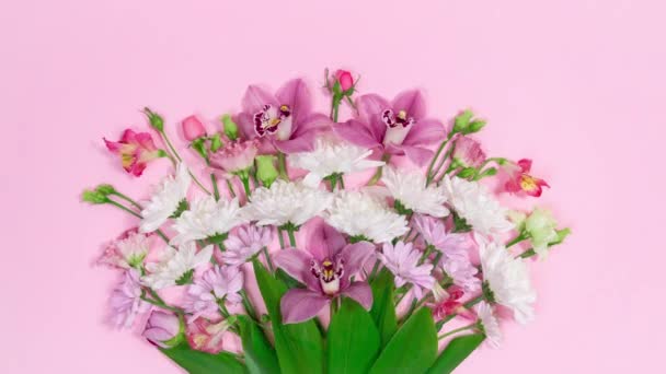 Όμορφο μπουκέτο από φυσικά λουλούδια εμφανίζεται σε ροζ φόντο. Ευχετήρια κάρτα για τα γενέθλια, την ημέρα της μητέρας, την ημέρα της γυναίκας ή άλλη περίσταση. Σταματήστε το κινούμενο σχέδιο. Αντιγραφή χώρου. Επίπεδη τοποθέτηση. - Πλάνα, βίντεο