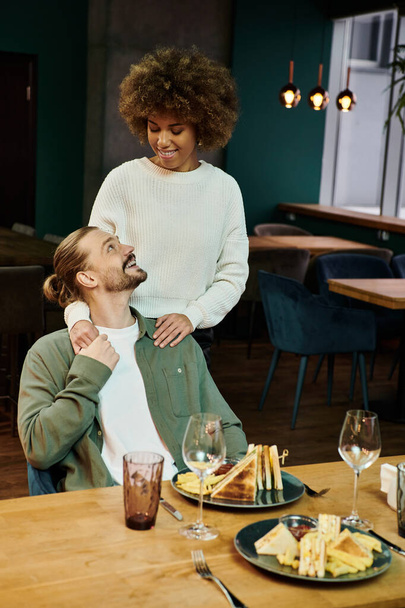 アフリカ系アメリカ人女性と男性が,現代のカフェでテーブルに座りながら会話をする.. - 写真・画像
