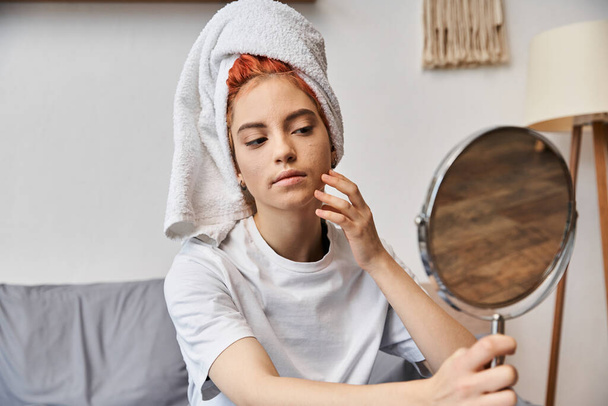 ελκυστικό υπερβολικό πρόσωπο με λευκή πετσέτα μαλλιών κοιτάζοντας στον καθρέφτη κατά τη διάρκεια της ρουτίνας πρωί στο σπίτι - Φωτογραφία, εικόνα