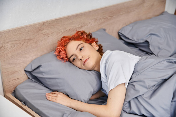 stravagante giovane queer persona in abbigliamento casual svegliarsi e stretching nel suo letto, tempo libero - Foto, immagini