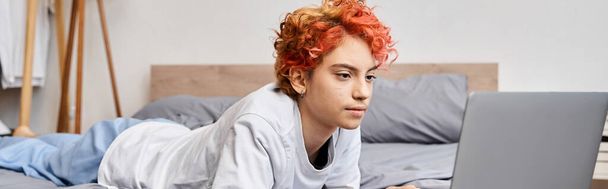 ελκυστική queer πρόσωπο στο άνετο homewear που βρίσκεται στο κρεβάτι και σέρφινγκ στο διαδίκτυο, ελεύθερος χρόνος, πανό - Φωτογραφία, εικόνα