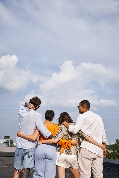 Rückansicht der Gruppe von interrassischen Freund in bequemen lebendigen Kleidern posiert auf dem Dach zusammen - Foto, Bild