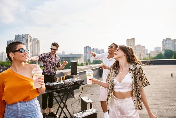 cheerful interracial friends with sunglasses drinking alcohol at rooftop party and dancing to DJ set - Foto, immagini
