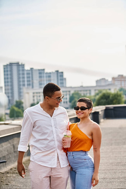amis interracial joyeux avec des lunettes de soleil en tenue vibrante boire et faire la fête sur le toit - Photo, image