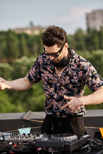 przystojny wesoły człowiek w żywy strój z okularami przeciwsłonecznymi gra muzykę jako DJ na dachu party - Zdjęcie, obraz