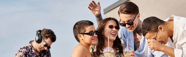 joyous interracial friends holding drinks and having fun next to DJ at rooftop party, banner - Photo, Image