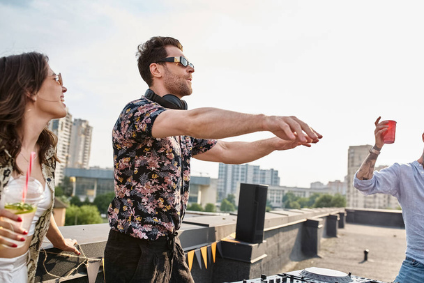 young good looking jolly people in stylish attires with cocktails dancing with DJ at rooftop party - 写真・画像