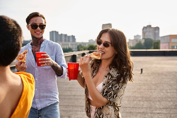 cheerful good looking friends in casual vivid attires eating pizza and enjoying drinks at party - Foto, imagen