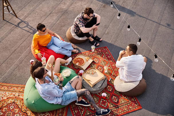 top view of five multiracial jolly friends enjoying pizza and cocktails at rooftop party together - Zdjęcie, obraz