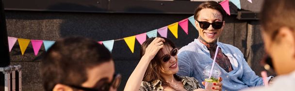 vrolijke jonge vrienden met trendy zonnebril zittend op het dak en cocktails drinkend op feest, spandoek - Foto, afbeelding