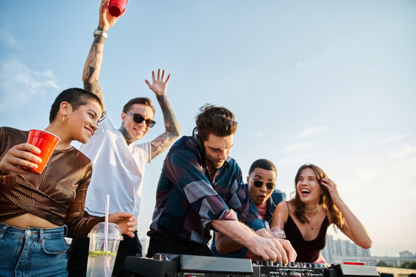 alegre atractivo diversas personas beber cócteles en la fiesta en la azotea y bailar con apuesto DJ - Foto, Imagen