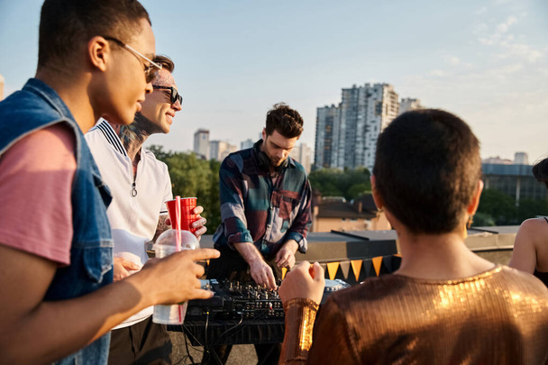 привлекательные разнообразные веселые друзья пьют и веселятся на вечеринке на крыше и наслаждаются DJ набор - Фото, изображение
