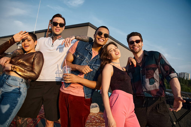 fröhlich gut aussehende multikulturelle Menschen in stylischer Kleidung lächeln bei Dachparty in die Kamera - Foto, Bild