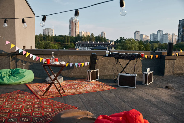 objeto foto de terraza al aire libre azotea con alfombras vibrantes y equipo de DJ con detalles de la fiesta - Foto, Imagen