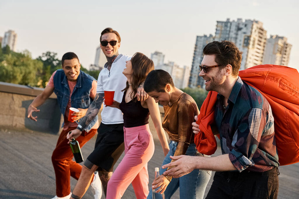 веселые мультикультурные друзья с различными напитками и креслом из бобов в руках на вечеринке на крыше - Фото, изображение