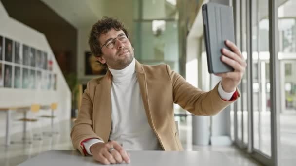 Hombre feliz en elegante casual tomando selfie en interiores con luz natural y fondo de oficina moderno - Metraje, vídeo