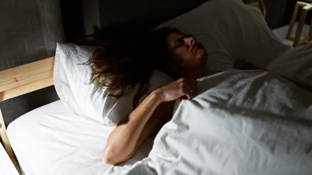 Egy fiatal nő békésen pihen egy sötét hálószobában, kiemelve a nyugalom és a pihenés hangulatát.. - Felvétel, videó