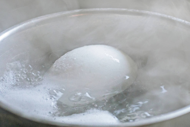 primer plano de un huevo de gallina cocido en agua hervida - Foto, Imagen