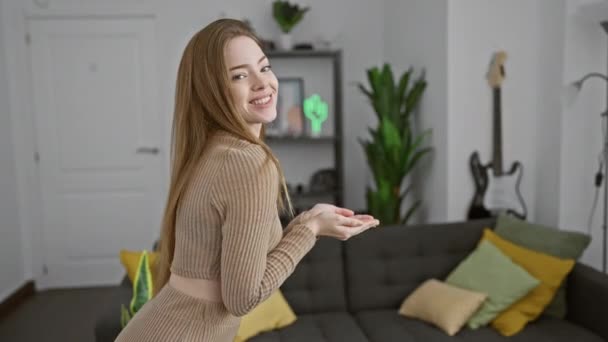 Nuori blondi nainen yllään villapaita osoittaa sivuun kädet auki kämmenet osoittavat kopioi tilaa, esittää mainos hymyillen innoissaan onnellinen kotona - Materiaali, video