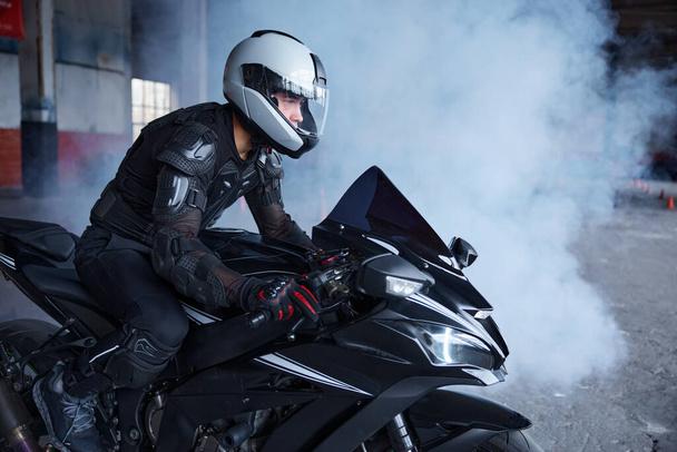 Motociclista usando capacete de proteção e uniforme para andar de velocidade na classe de treinamento do autódromo da escola de condução profissional - Foto, Imagem