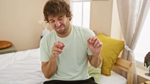 Ällöttävä pyjama-verhottu nuori valkoihoinen mies makuuhuoneessa osoittaa vastenmielisyyttä pelokkailla kasvoilla ja nostamalla kädet - Materiaali, video