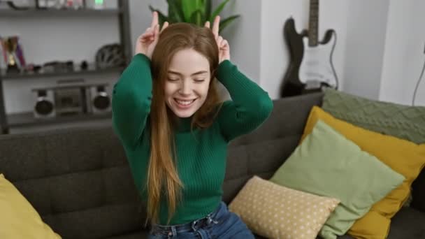 Fiatal szőke nő pulóvert visel pózol vicces és őrült ujjakkal a fején, mint nyuszifül, mosolyogva vidám otthon - Felvétel, videó