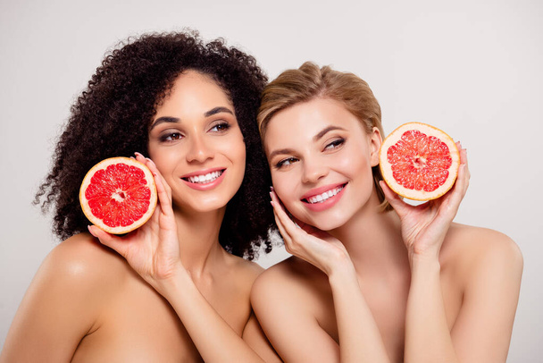 Foto de hermosas chicas impresionantes sostienen naranja fruta rebanada mirar sobre pegar espacio vacío fondo toque cara perfecta. - Foto, imagen