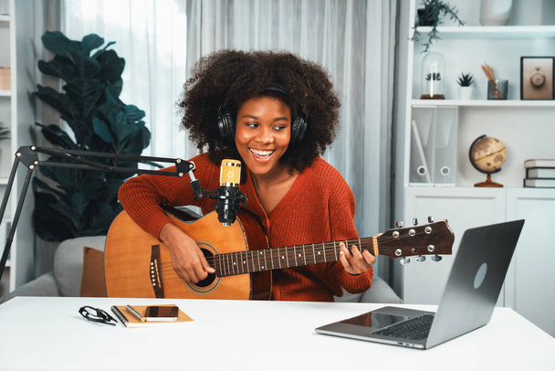 Hostitelský kanál v hudebník mladých Afroameričanů hrající na kytaru spolu se zpěvem, vysílání na notebooku ve studiu. Výzdoba vybavení sluchátek a záznamového mikrofonu. Tastemaker. - Fotografie, Obrázek