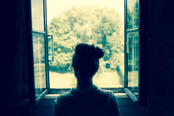 Woman looking through the window - Foto, Bild