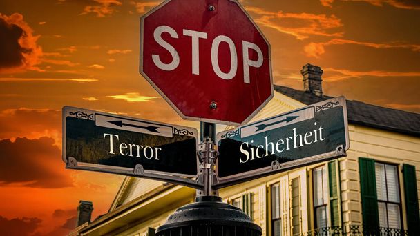 Egy kép egy táblával, ami két különböző irányba mutat németül. Az egyik irány a biztonságra mutat, a másik a terrorra.. - Fotó, kép
