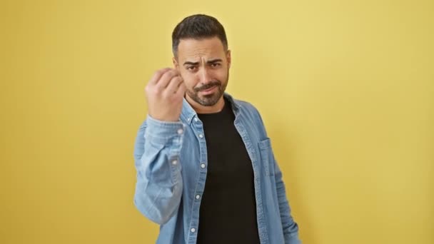 Красивий молодий іспаномовний чоловік у джинсовій сорочці впевнено виконує італійський жест рук, стоїть ізольовано на яскравому жовтому тлі - Кадри, відео
